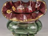 a green vase with a red flower inside of it
