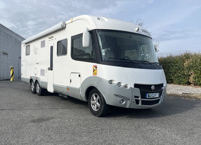un camping-car blanc garé sur un parking à côté d'un immeuble