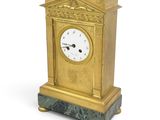 une horloge dorée posée sur un socle en marbre, sur fond blanc