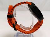 an orange watch with a black band sitting on a clear stand