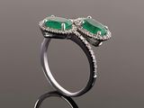 a close up of two emerald and diamond rings on a reflective surface