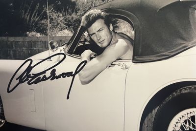 photographie en noir et blanc d'un homme assis dans une voiture, la main sur le volant