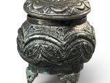 an ornate metal box with a lid on a white background