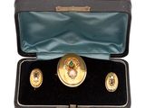 a box with three gold and green brooches in it
