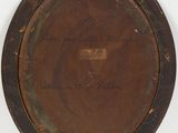 an old brown plate with writing on it sitting on a white surface