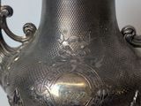 a silver vase that has a handle on it