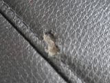 a close up of a black leather bag with a hole in it