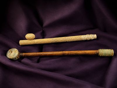 two wooden baseball bats and a ball on a purple cloth