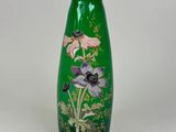 un vase vert orné de fleurs, posé sur une surface blanche