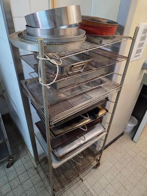 une photo d'une cuisine dans laquelle se trouve une étagère sur laquelle sont posées des casseroles et des poêles