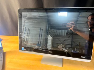 un homme en train de prendre une photo de l'écran d'un ordinateur posé sur un bureau