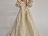 a doll that is wearing a white dress and a bonnet