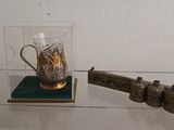 a glass display case with a gun and a glass cup on it