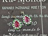 une paire de boucles d'oreilles roses et vertes exposée devant une enseigne « ka - mondo »