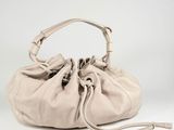 the large beige bag is sitting on a white surface