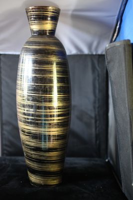 un vase noir et doré posé sur un canapé noir