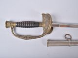 une épée avec une poignée et deux autres objets posés sur une surface blanche