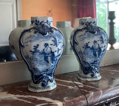 two blue and white vases sitting on a mantle