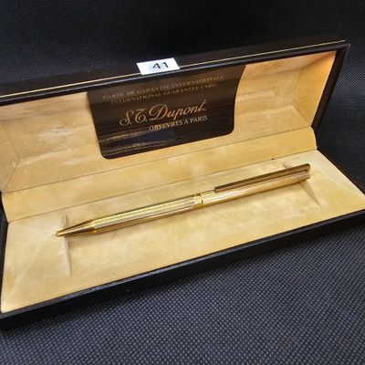 un stylo doré dans un coffret noir sur fond noir