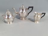 three pieces of silver tea and coffee set on a table