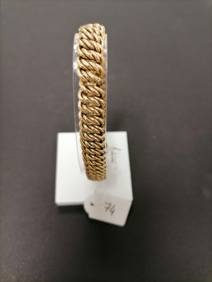 a close up of a gold bracelet on a stand on a table