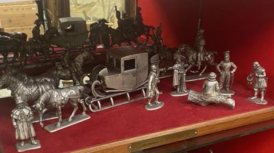 figurines en argent représentant des chevaux, des calèches et des attelages sur un fond rouge