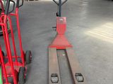 un chariot élévateur rouge et un diable rouge dans un entrepôt