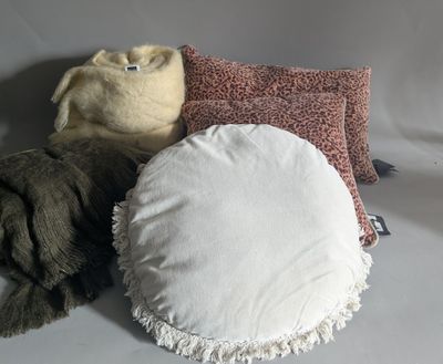 three pillows and a blanket on a white surface