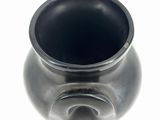 a black vase that is sitting on a white surface