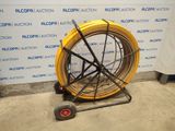 a yellow hose sitting on a cart in front of a wall