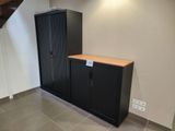 une armoire noire sur laquelle est accrochée une pancarte, dans un coin de la pièce