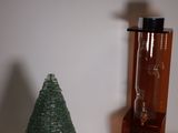 un petit sapin de Noël posé à côté d'une bouteille en verre sur une table