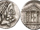 a silver coin with a woman ' s head and a building on it