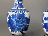 pair of blue and white vases sitting on a wooden stand