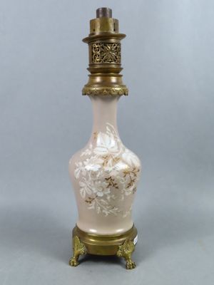 un vase blanc et doré posé sur un socle surmonté d'une lampe