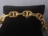 gold plated bracelet with chain links and clasps on a black velvet cushion