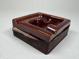 un cendrier marron et noir posé sur une table blanche