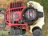 a man holding a lawn mower with a hose attached to it