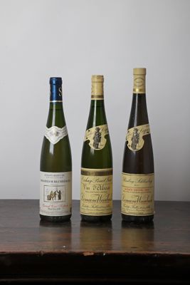 trois bouteilles de vin sont alignées sur une table en bois