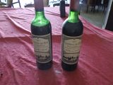 deux bouteilles de vin posées sur une table recouverte d'une nappe rouge