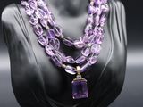 a close up of a mannequin with a purple necklace on it