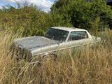 une vieille voiture abandonnée dans les hautes herbes