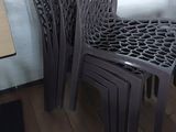 several plastic chairs and a table in a room with wood flooring