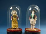 two miniature figurines of people under a glass dome