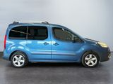 the small blue van is parked in a room with a gray wall