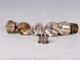 several different types of metal cups are lined up on a white surface