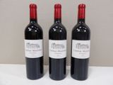 three bottles of red wine are lined up on a table