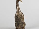 bronze sculpture of a duck on its hind legs on a white surface