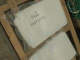 a pallet of white toilet paper on a pallet next to a pile of other toilet paper