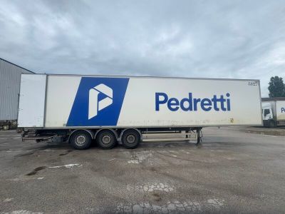 a white semi trailer parked in a parking lot next to a building